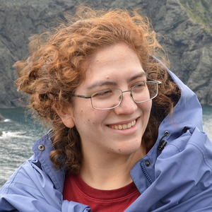 A photo of a tiny Asena Goren standing in a large rocky landscape.